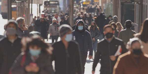 Busy street with people wearing respiratory masks facing towards camera