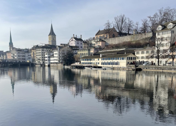 View from bridge with quiet calm river in foreground and buildings on other side in Zurich Switzerland on a sunny day.