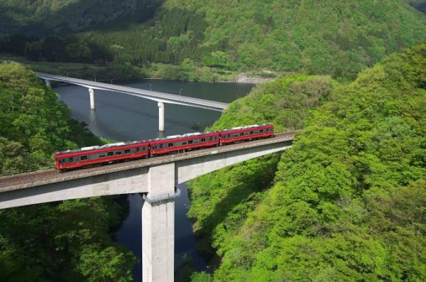 Red Aizu Railway train travelling over a tall concrete viaduct