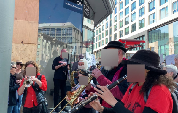 Three people in red play brass instruments at the protest.