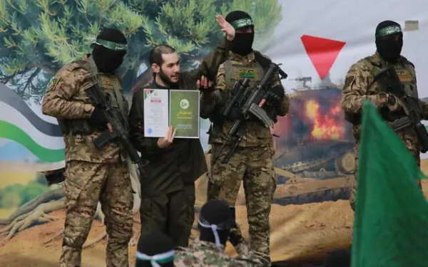 Israeli hostage Eliya Cohen, flanked by Palestinian Hamas fighters, waves under duress before being released along with two others in Nuseirat in the central Gaza Strip, on February 22, 2025. (Bashar TALEB / AFP)