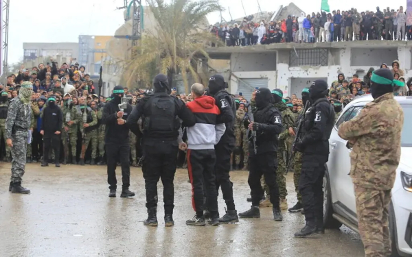 Hamas members parade an Israeli hostage before transferring him to the Red Cross, as part of the ceasefire agreement between Israel and Hamas, in Rafah, February 22, 2025. (Abed Rahim Khatib/Flash90)