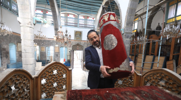 A rabbi holds a Torah inside a historic synagogue in Syria