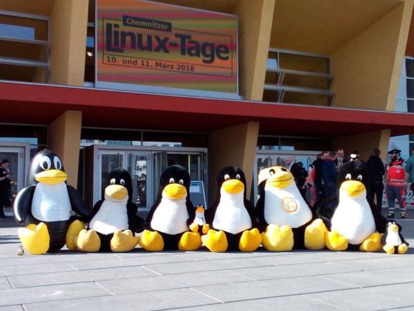 Eine Gruppe aus mehreren großen und kleinen Plüschpinguinen, die alle zusammen für die Gruppe an Helfer:innen der Chemnitzer Linux-Tage stehen.