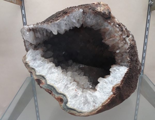 A big, round hollow rock (geode). The vanity is filled with white quartz crystals, and around the outer rims are grey coloured bands of agate.