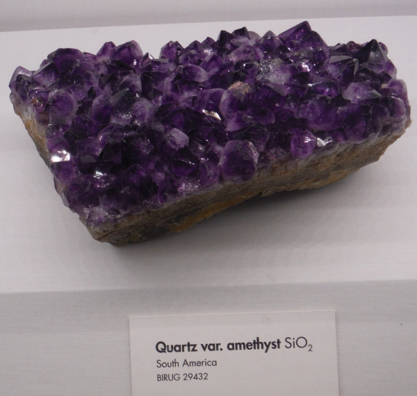 A cluster of shiny purple amethyst crystals.

Label text: Quartz var. amethyst SiO2. South America. BIRUG 29432.