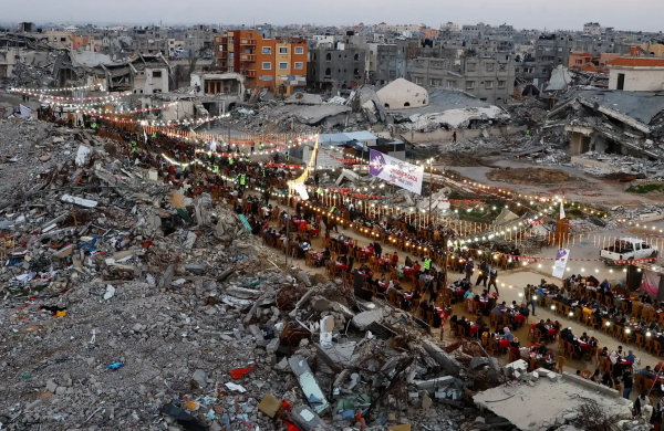 Long row of tables and lights in a cleared area surrounded by rubble.