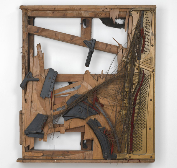 Sculpture of a large wooden frame of a smashed-apart instrument, with metal wire bursting outward and various other broken parts exposed.