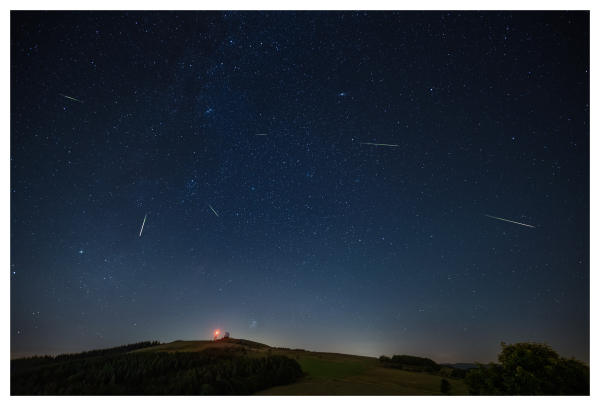 The picture shows a meteor shower over the Wasserkuppe, the highest mountain in the Rhön, a low mountain range in Germany.