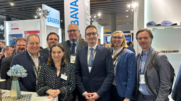 Gruppenbild mit Staatssekretär Stefan Schnorr, Mitarbeiterinnen und Mitarbeitern des BDMV sowie Vertreterinnen und Vertretern des Freistaats Bayern am landeseigenen Stand auf dem Mobile World Congress.