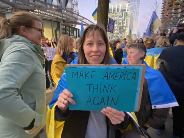 Woman holding a blue and yellow placard reading MAKE AMERICA THINK AGAIN