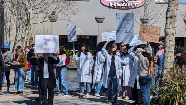 A gathering of scientists in the street holding placards