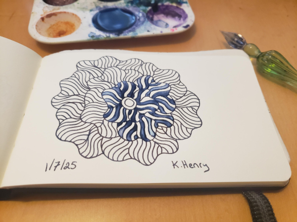 Hand drawn generative/procedural art in ink on an open page of my sketchbook. The abstract pattern is floral. My glass dipping pen and ink palate are next to my sketchbook.