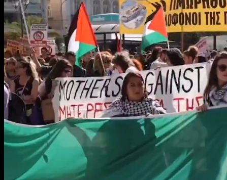 Huge crowd marching behind an enormous Palestinian flag