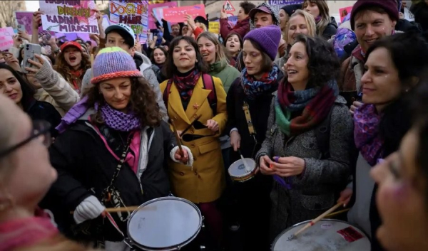 Women surround a lady playing a drum in Warsaw