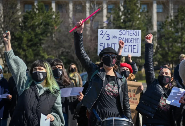 Women in facemasks with raised fists protest in Bucharest