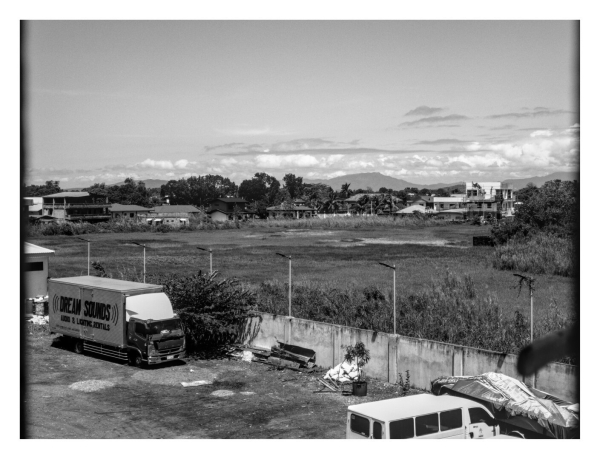 A black and white photograph depicting a landscape with a mix of urban and rural elements, taken from an elevated perspective. - Google Gemini