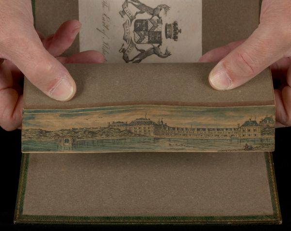 Scene of a long building along a waterfront, painted on the edge of a book